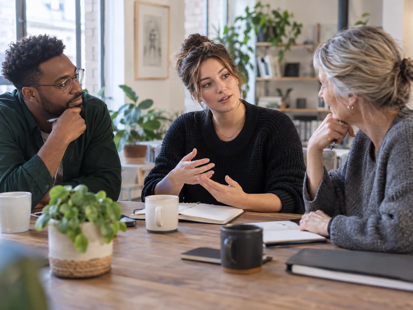 Three colleagues sharing perspectives around a table